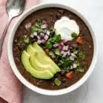Black Bean Soup topped with avocado, sour cream, red onion, cilantro, and fresh lime