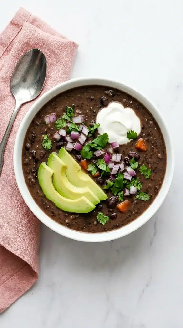 Black Bean Soup topped with avocado, sour cream, red onion, cilantro, and fresh lime