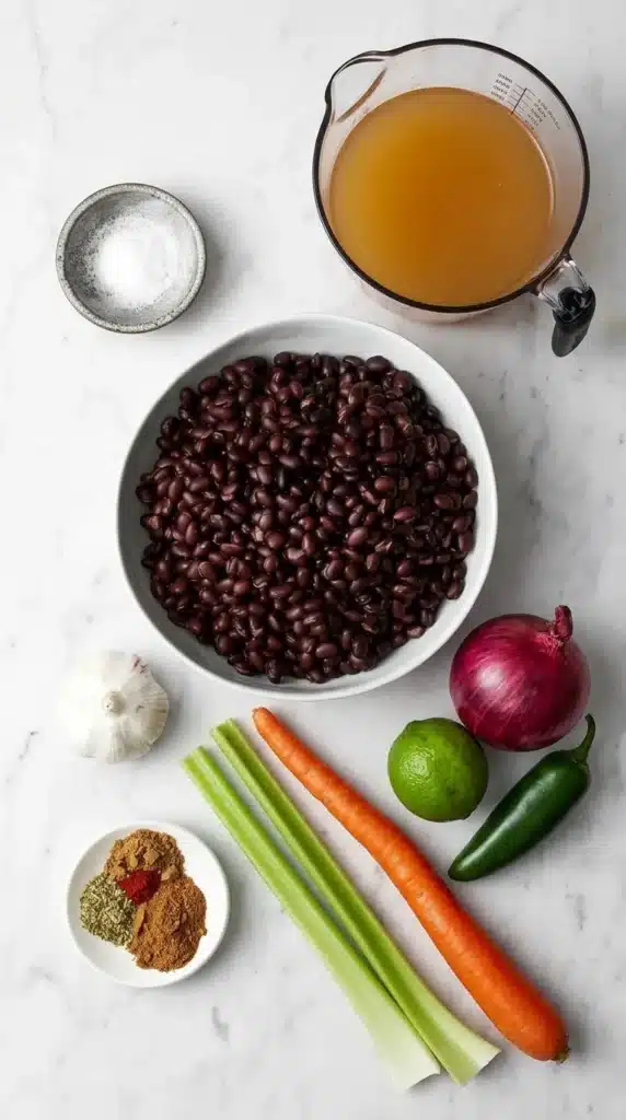 Black Bean Soup ingredients with black beans, vegetables, spices, broth, garlic, and lime