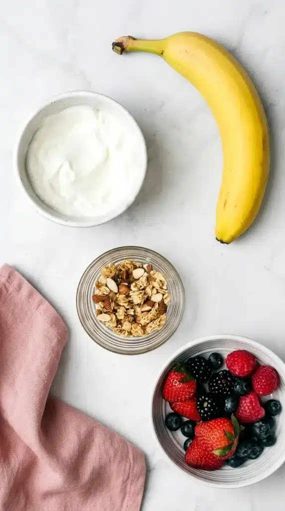 Breakfast Banana Split ingredients with banana, Greek yogurt, berries, and granola