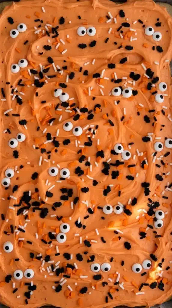 The Best Easy Halloween Sugar Cookie Bars with orange frosting, sprinkles, and candy eyeballs