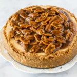 Pecan Pie Cheesecake with creamy filling, graham crust, and glossy caramel pecan topping