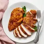 Air Fryer Chicken Breast: Amazing Juicy Results in 15 Min 4 Juicy Air Fryer Chicken Breast sliced on a ceramic plate with golden paprika seasoning and fresh herbs