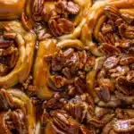 Butter Pecan Cinnamon Buns topped with glossy caramel glaze and crunchy toasted pecans