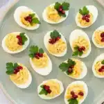 Christmas Deviled Eggs: Easy, Beautiful Holiday Bites 5 Christmas Deviled Eggs with creamy yolk filling, fresh parsley and ruby red pomegranate seeds on a festive platter