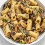 Creamy Hummus Pasta with mushrooms in a bowl topped with fresh parsley