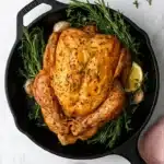 Easy Roast Chicken with golden crispy skin, fresh herbs, and Italian seasoning in a cast-iron skillet.