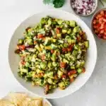 Overhead bowl of Avocado Salsa with tomatoes, red onion, cilantro, and tortilla chips