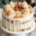 Christmas spice cake with eggnog buttercream, cinnamon dusting, creamy frosting drips, and festive decorations.
