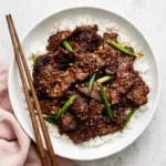 Mongolian Beef with tender glazed steak, fluffy white rice, and fresh green onions in a ceramic bowl