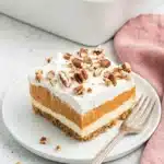Pumpkin Lush slice with graham cracker crust, pumpkin pudding, whipped topping, and pecans