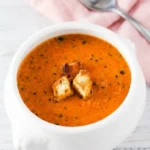 Roasted Tomato Basil Soup with creamy tomatoes, fresh herbs, golden garlic croutons, and toasted grilled cheese.
